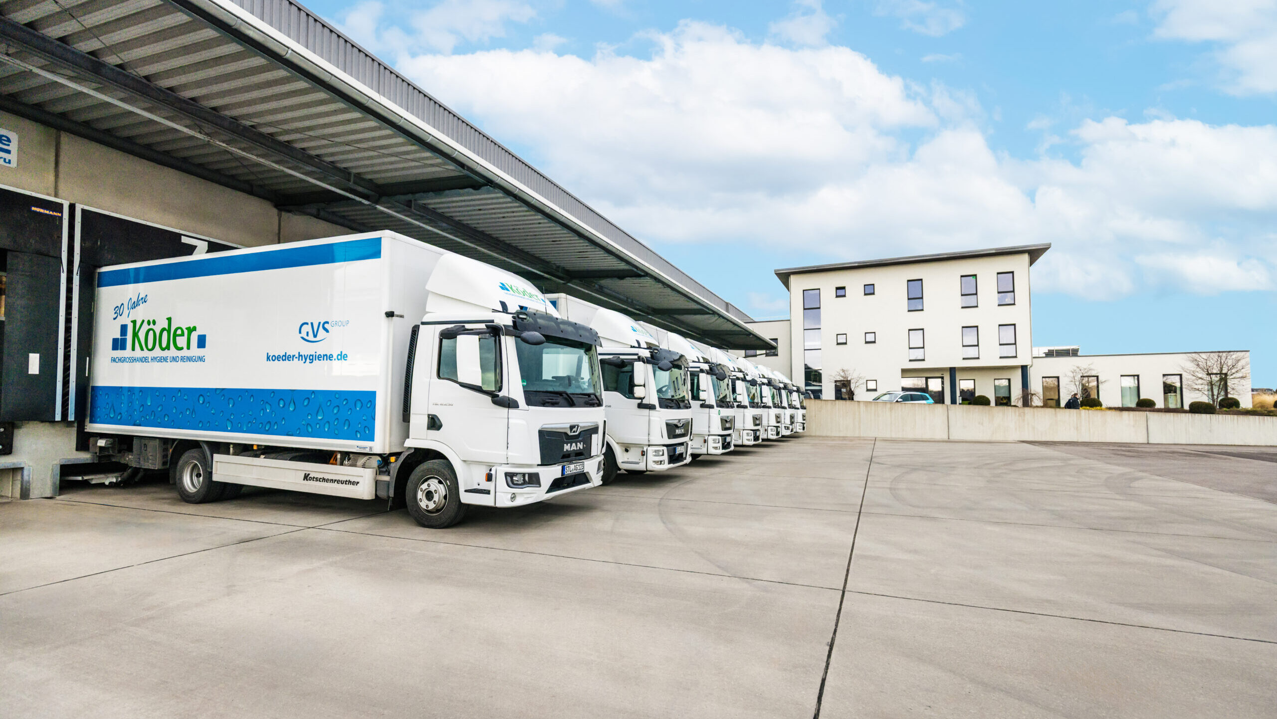 Eine Flotte weißer Lkw des Fachgroßhandels Köder Hygiene ordentlich aufgereiht auf dem Betriebshof.