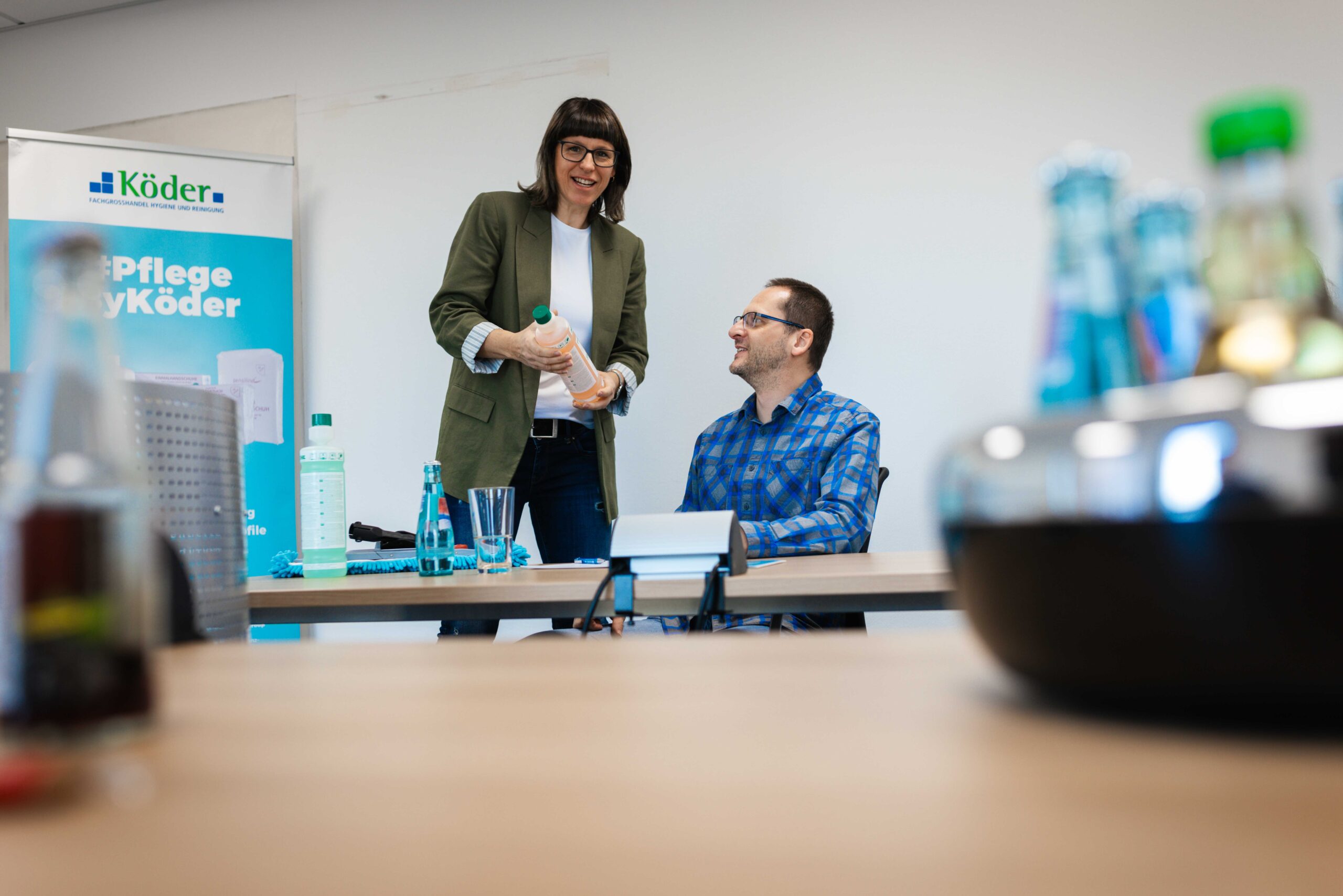 eine Mitarbeiterin von Köder Hygiene zeigt einem Teilnehmer die Grundlagen der Reinigung im Schulungsraum.